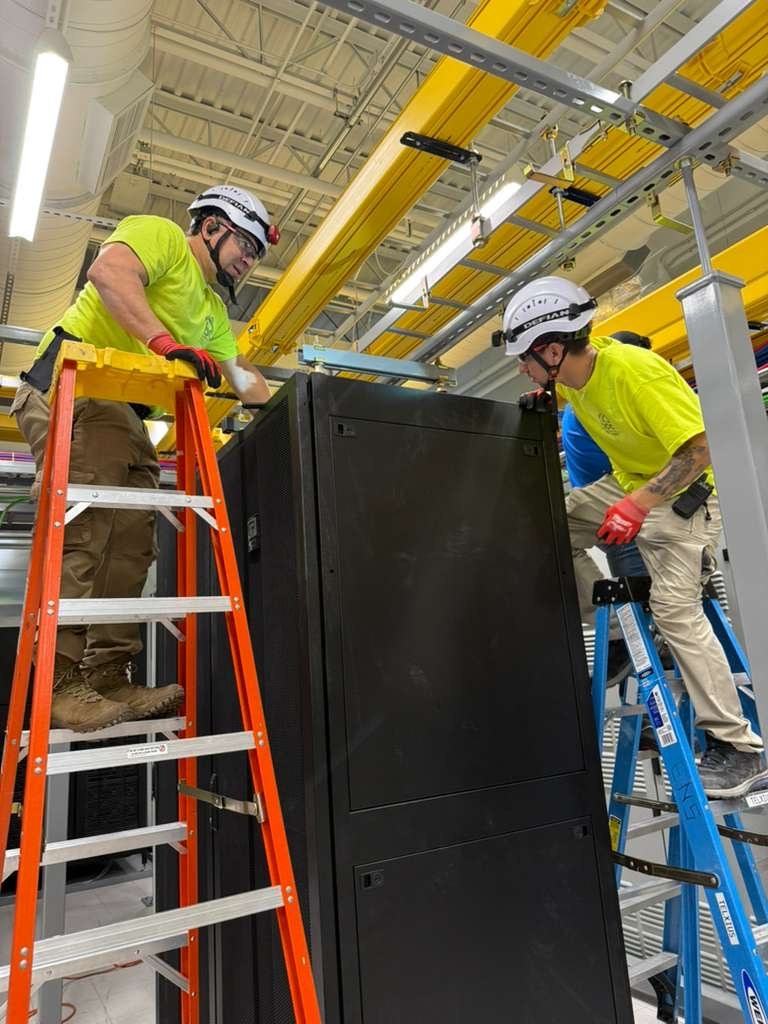 Crew positioning a cabinet on ladders during installation